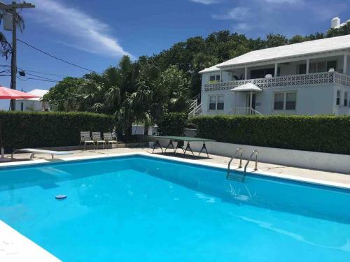a large blue swimming pool in front of a house at Bermuda At the Beach One-Bedroom in Paget Parish