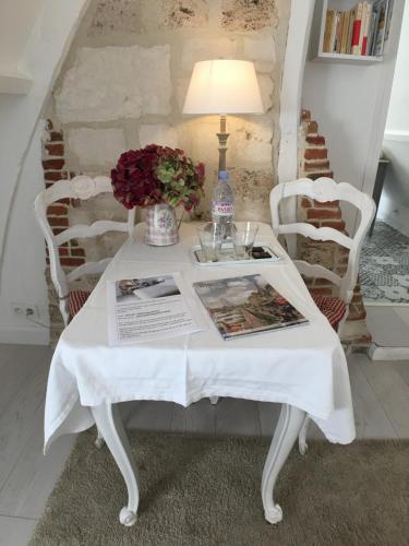 a white table with a lamp and flowers on it at La Romance et la Romanesque in Berville-sur-Mer