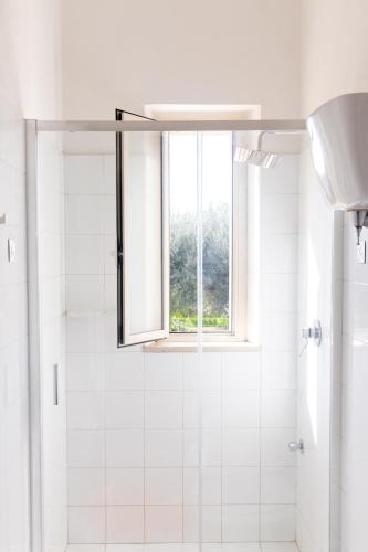 a white bathroom with a shower with a window at Case Costa Degli Dei in Santa Domenica