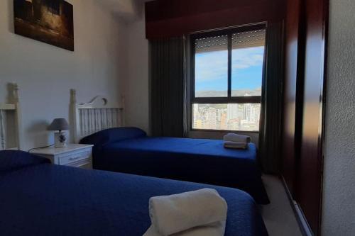 a bedroom with two blue beds and a window at BENIDORM GEMELOS II ONE, impresionante vista in Benidorm