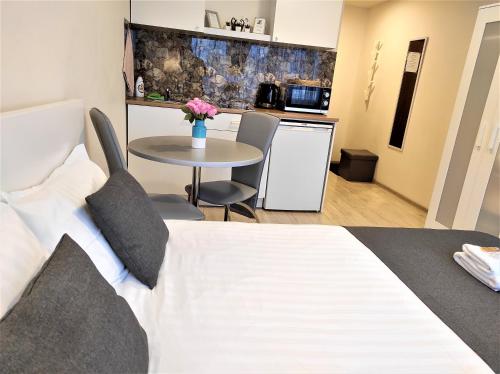 ein Schlafzimmer mit Bett und Tisch und eine Küche in der Unterkunft Klaipeda Akro Studio in Klaipėda