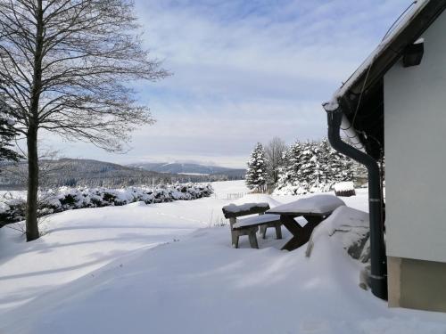 a picnic table covered in snow next to a house at Chata Krušnohorka in Kovářská