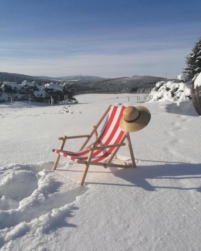 a beach chair with a hat sitting in the snow at Chata Krušnohorka in Kovářská
