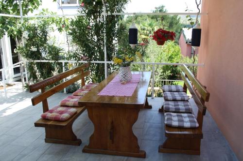 une table en bois avec des bancs rembourrés sur une terrasse dans l'établissement Apartments Mihoci, à Rogoznica
