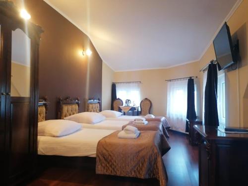 a bedroom with two beds and a tv on the wall at Gościniec & SPA Darłowo in Darłowo
