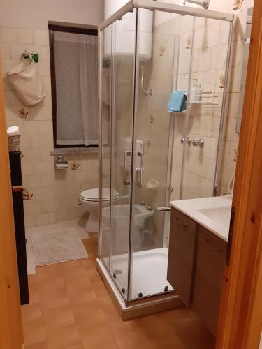 y baño con ducha, aseo y lavamanos. en Appartamento arredato con angolo cottura, en Argentera