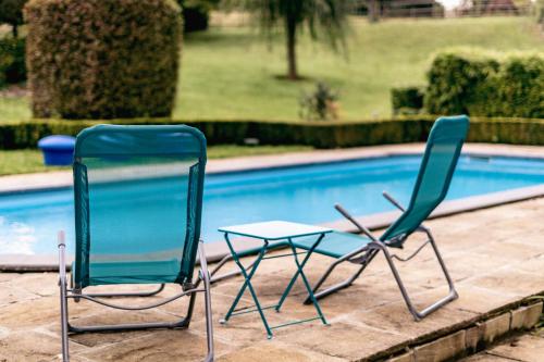 two chairs sitting next to a swimming pool at Au bout de mes rêves in Walcourt
