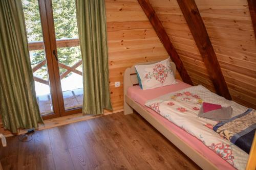 a bedroom with a bed in a log cabin at Ville Uskoci in Žabljak