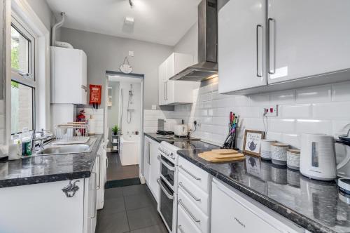 a kitchen with white cabinets and a sink at 2BR Cosy Stay Near Cathedral Parking Workspace in Norwich