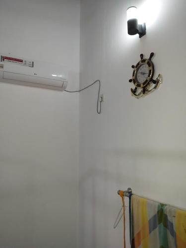 a clock on a white wall with a lamp at RAJASINGHE Guest in Kaduwela