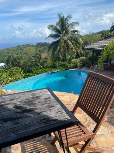a table and a chair next to a swimming pool at Globe trotter Lodge Tahiti in Punaauia