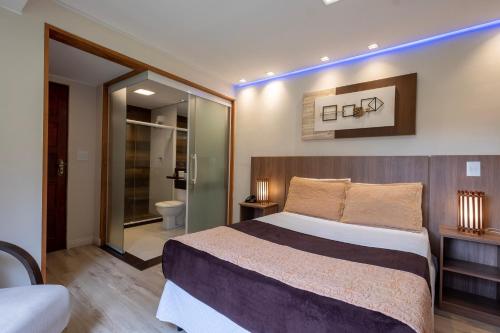 a bedroom with a large bed and a bathroom at Hotel Serra Everest in Nova Friburgo