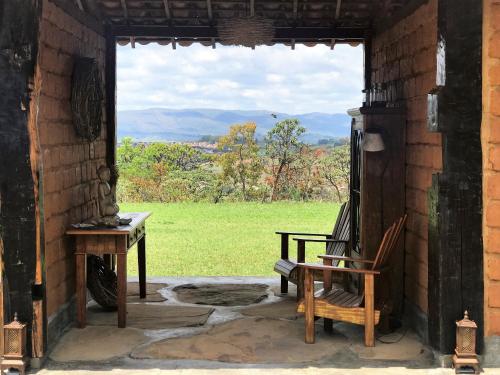 a porch with a chair and a window with a view at Pousada Sete Quedas in Carrancas