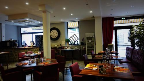 a restaurant with tables and chairs and a clock on the wall at Hotel-Restaurant des Voyageurs in Le Cheylard