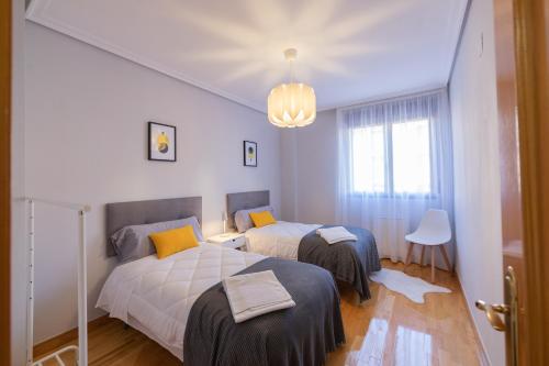 1 dormitorio con 2 camas y lámpara de araña en Apartamento Albelda Centro en Albelda de Iregua
