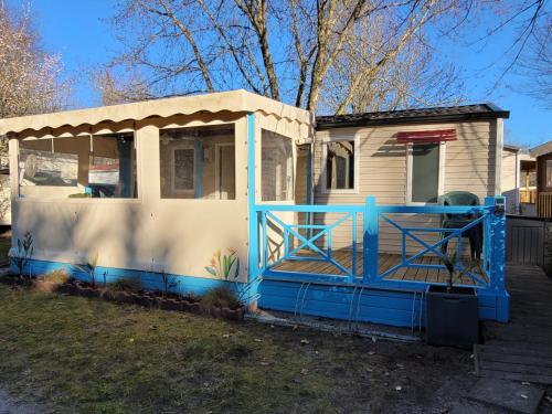 une maison bleue et blanche avec une terrasse couverte dans l'établissement Mobil Home Plage Lac Parentis/Biscarosse, à Parentis-en-Born