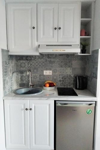 a kitchen with white cabinets and a sink at Katerina Studios in Naxos Chora