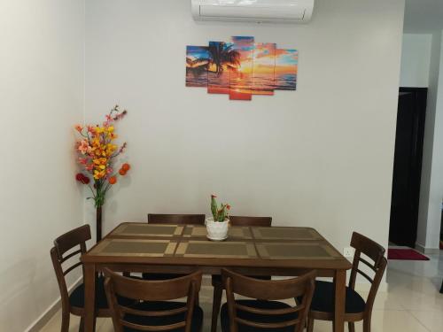 a dining room table with chairs and a painting on the wall at 48 悠之处NO . 48, PERSIARAN ALAM IMPIAN 3 VILLA RIADAH ALAM IMPIAN PANGKOR, 32300 PANGKOR , PERAK. in Pangkor