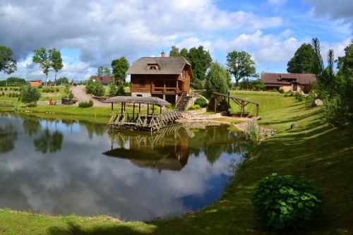 a log cabin sitting next to a lake at Sodyba Tarp Liepų in Leliūnai