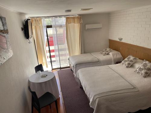 a room with two beds and a table and a window at Hotel Diaguitas Illapel in Illapel