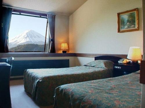 um quarto de hotel com duas camas e vista para a montanha em Guesthouse Sakuya em Fujikawaguchiko