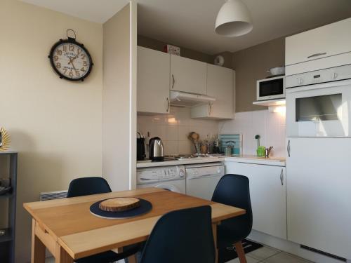 une cuisine avec une table en bois et une horloge au mur dans l'établissement Résidence Long Island, à Cayeux-sur-Mer