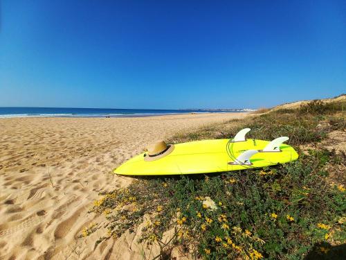 a yellow surfboard sitting on a sandy beach at Regenbogen Properties - Salgados Vila das Lagoas in Albufeira