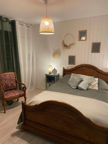 ein Schlafzimmer mit einem Holzbett und einem Stuhl in der Unterkunft Les Hortensias de Marie in Laviéville