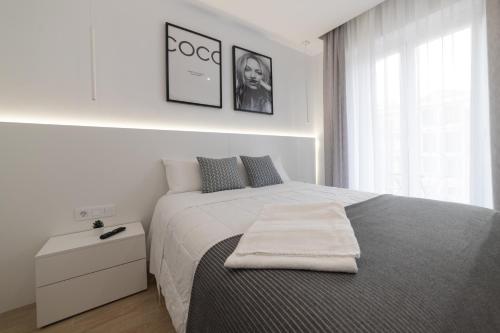 Un dormitorio blanco con una cama con una toalla. en Apartamento Ayuntamiento Av de La Paz en Logroño