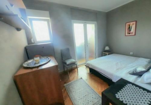 een kleine slaapkamer met een bed, een tafel en een raam bij Iva in Belgrado