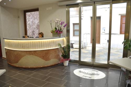 a woman sitting at a counter in a lobby at Hotel Biancolilla in San Vito lo Capo