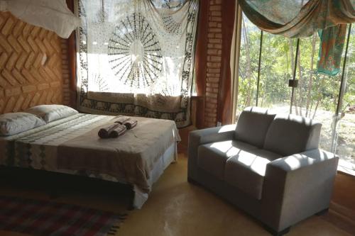 a bedroom with a bed and a chair and a window at Chalé na Chapada, com acesso ao Rio São Miguel in Sao Jorge