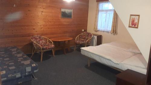 sypialnia z łóżkiem, stołem i 2 krzesłami w obiekcie Pension Paulů w mieście Pec pod Sněžkou