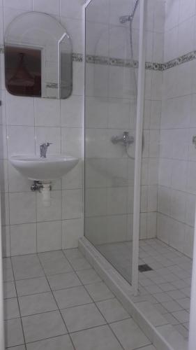 La salle de bains blanche est pourvue d'une douche et d'un lavabo. dans l'établissement Pension Paulů, à Pec pod Sněžkou