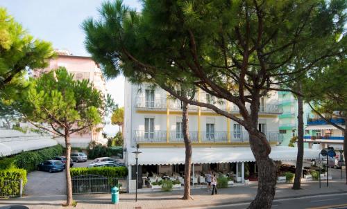 un edificio con balcón en una calle con árboles en Hotel Roma, en Lido di Jesolo