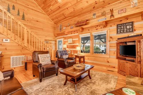 a living room with furniture and a tv in a log cabin at Boone Bounty in Boone