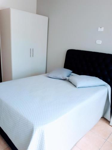a white bed with two pillows on top of it at Hospedaria São Benedito in Guararema