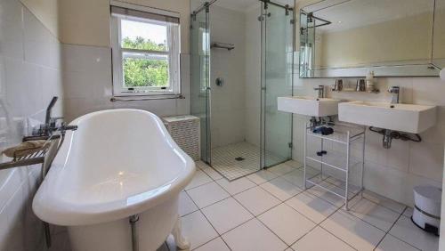 a bathroom with a tub and a sink and a shower at Belvidere102 in Knysna