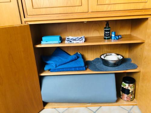 a cupboard with blue towels and a pot and a bowl at Haus Gerda Ferienwohnung 5 in Arnbruck