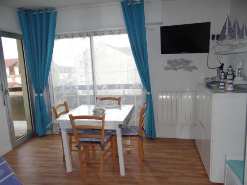 une salle à manger avec une table et des chaises blanches dans l'établissement Appartement Ste Cécile à 50 mètres de la plage, à Sainte-Cécile-Plage