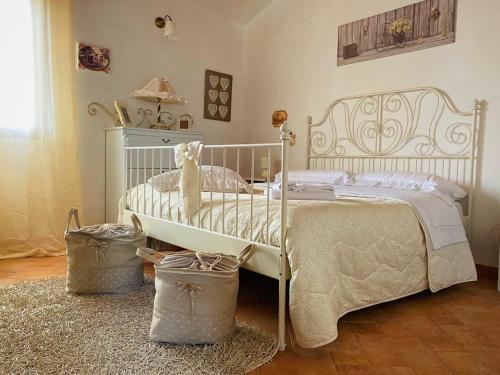 a white bed in a bedroom with two baskets at Il Rifugio della Quiete in Scicli