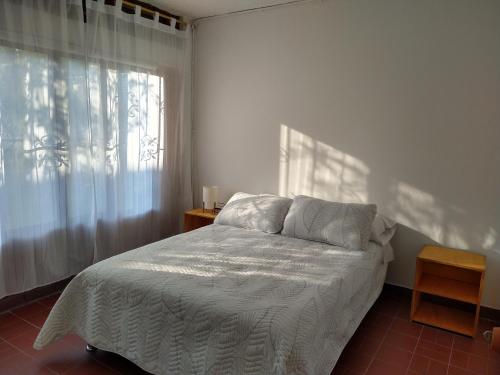 1 dormitorio con cama blanca y ventana en Pequeño Paraíso un lugar ventilado y acogedor, en El Placer