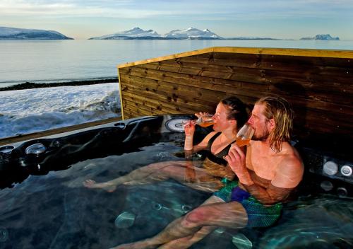 two men sitting in a hot tub drinking wine at Lyngen Experience Lodge in Nord-Lenangen
