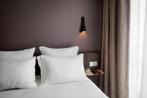 a bedroom with a bed with white pillows and a lamp at OKKO Hotels Lyon Centre in Lyon