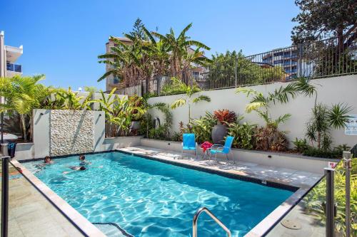 una piscina con 2 personas nadando en ella en Capeview Apartments - Right on Kings Beach, en Caloundra