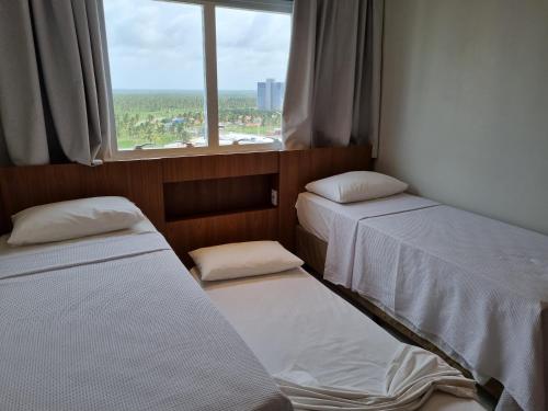 two beds in a small room with a window at CONFORTO E EXCLUSIVIDADE in Salinópolis