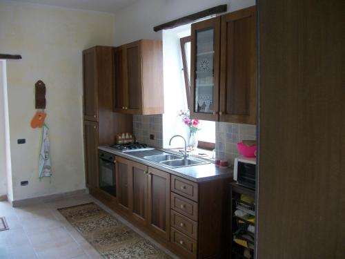 una cucina con armadi in legno, lavandino e finestra di Il Casale -appartamento di 105mq- a SantʼAgata deʼ Goti