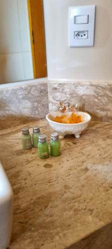 a bathroom counter with a sink and a bowl and green jars at Chalés Bella in Monte Verde