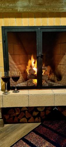 two glasses of wine in front of a fireplace at Chalés Bella in Monte Verde
