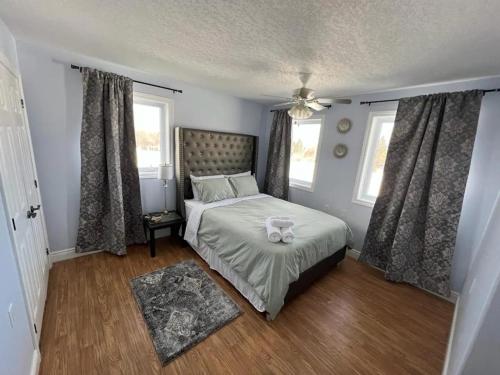 a bedroom with a bed and two windows at PlanURstay - Carrying Place 6BR & 3BTH Near SandBanks Park in Carrying Place